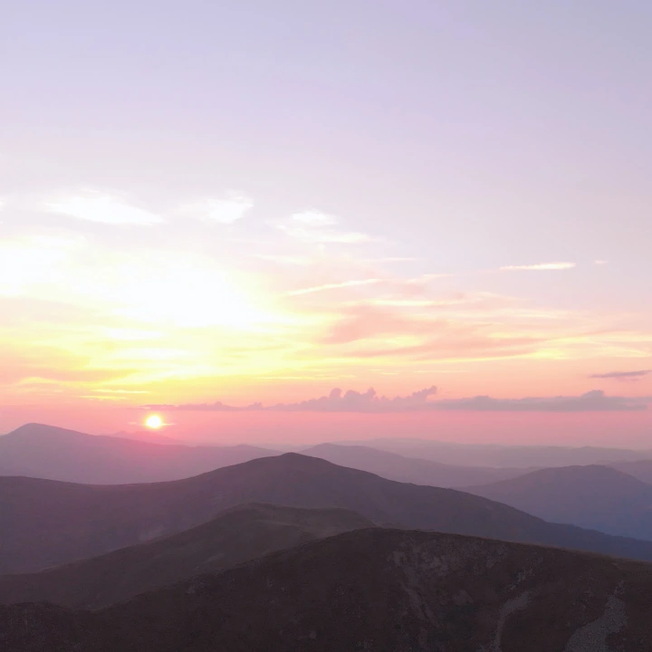 Pastel sunrise over layers of mountain peaks
